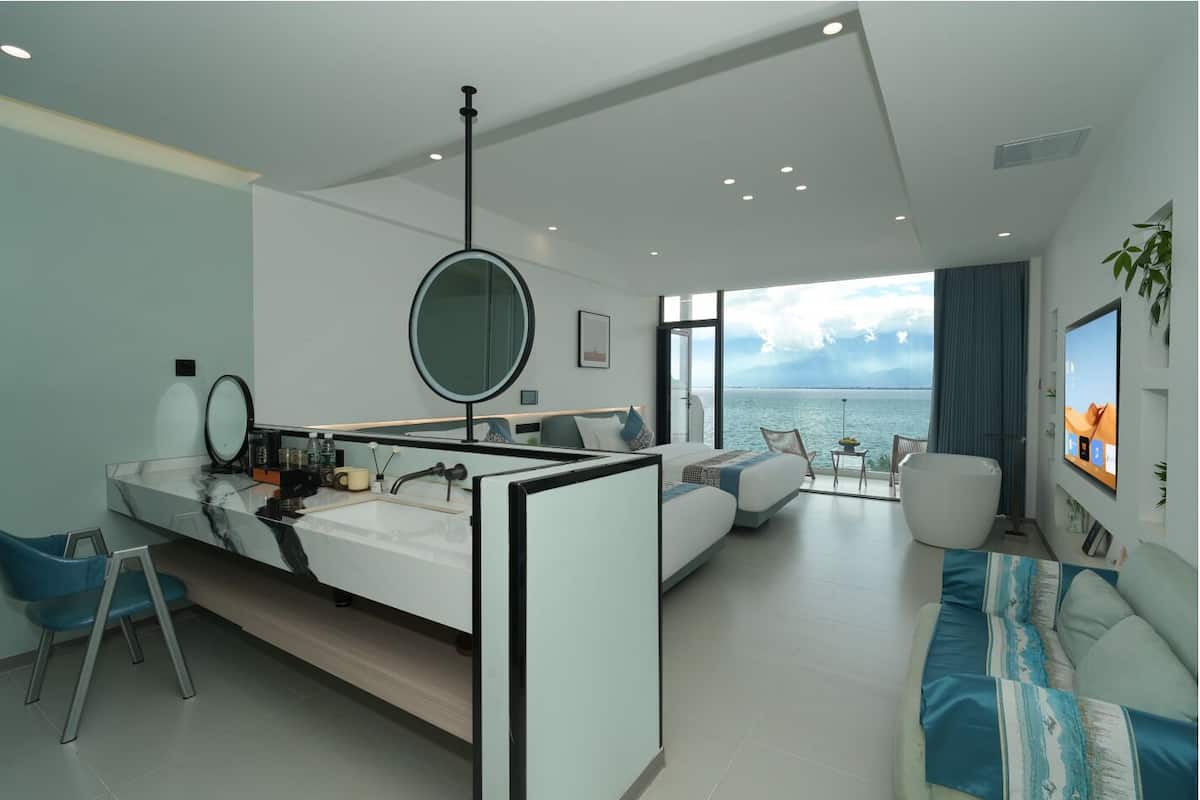 Un dormitorio moderno con una cama grande, un escritorio y vistas al mar.