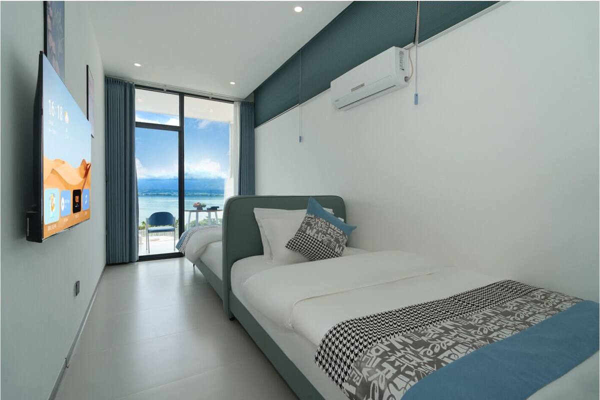 Una habitación de hotel moderna con una cama, un ventanal con vistas y un televisor de pared.