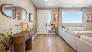 Ein modernes Wohnzimmer mit einer Couch, einem Holzkonsolentisch mit Lampe, einem Teleskop und einem großen Spiegel an der Wand.