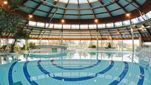 En inomhuspool med en rund form, stora fönster och ett högt tak.