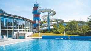 A swimming pool with a water slide, a tall tower, and a building with large windows. - Ferienwohnungen im Seepark Sellin (Sellin)