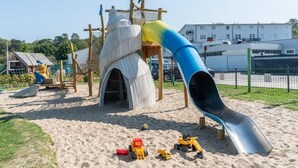 A playground with a slide, climbing structures, and sand. - Ferienwohnungen im Seepark Sellin (Sellin)