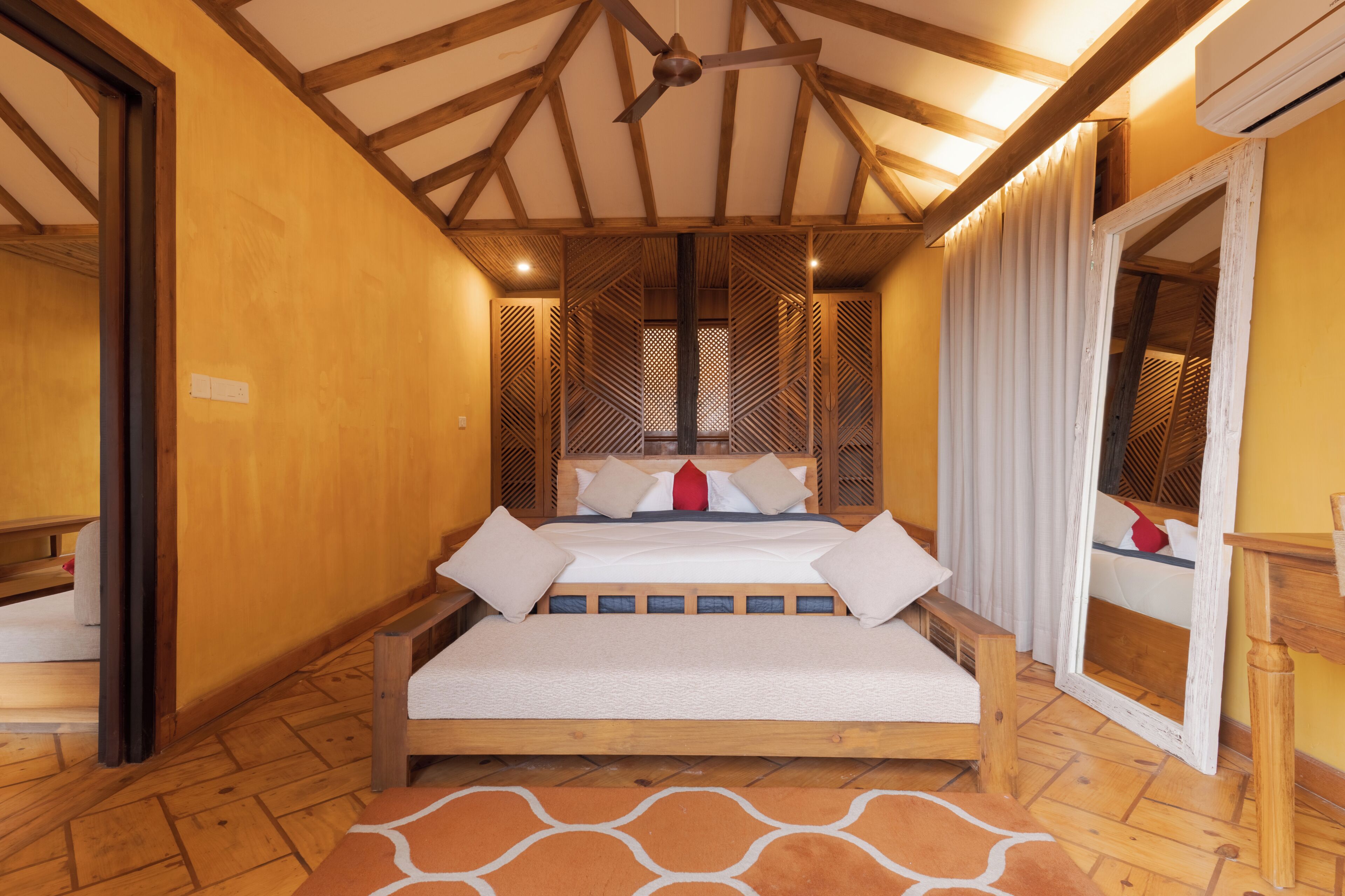 Ein Zimmer mit einem hölzernen Bett, einem Deckenventilator, einem Spiegel und einem gemusterten Teppich.