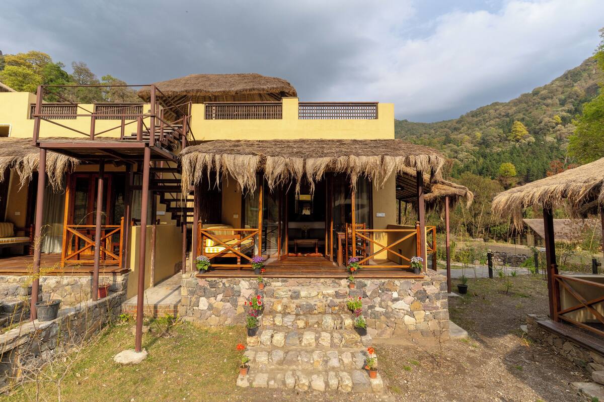Un edificio de dos pisos con techo de paja, escalones de piedra y barandillas de madera.