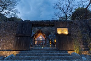 Un arco de piedra que conduce a un edificio de madera con un cartel que dice 'KANSYA RESORT'.