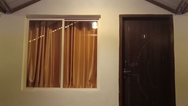 A building with a single window and a door, a small porch area, and a roof with lights. - Mountain View Cottage  (Rishikesh)