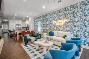 Ein modernes Wohnzimmer mit einem Schachbrettmuster-Teppich, einem weißen Sofa und blauen Sessel.