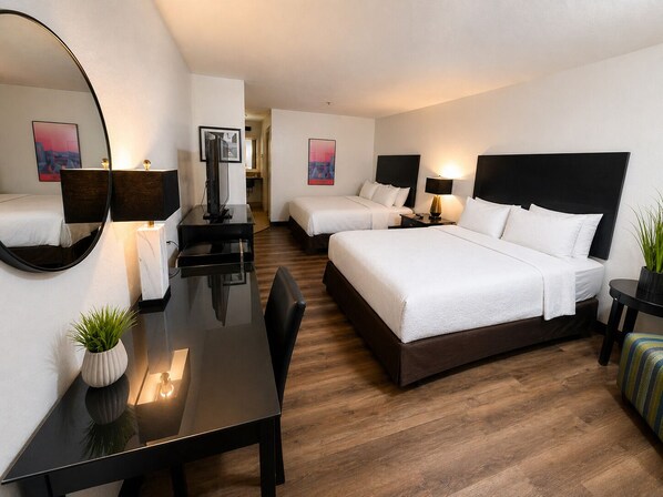 A hotel room with a large bed, a desk, a chair, a mirror, and a television.