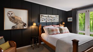 Ein Schlafzimmer mit einem großen Bett, einem Nachttisch, einem Sessel und Bildern an den Wänden.
