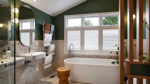 Ein modernes Badezimmer mit einer freistehenden Badewanne, zwei Waschbecken, einem Handtuchhalter und einem großen Spiegel.