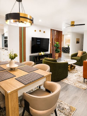 Ein modernes Wohnzimmer mit Fernseher, Sofa und Essbereich.