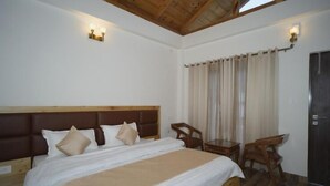 A bedroom with a large bed, wooden headboard, two bedside tables, a desk, and a chair.