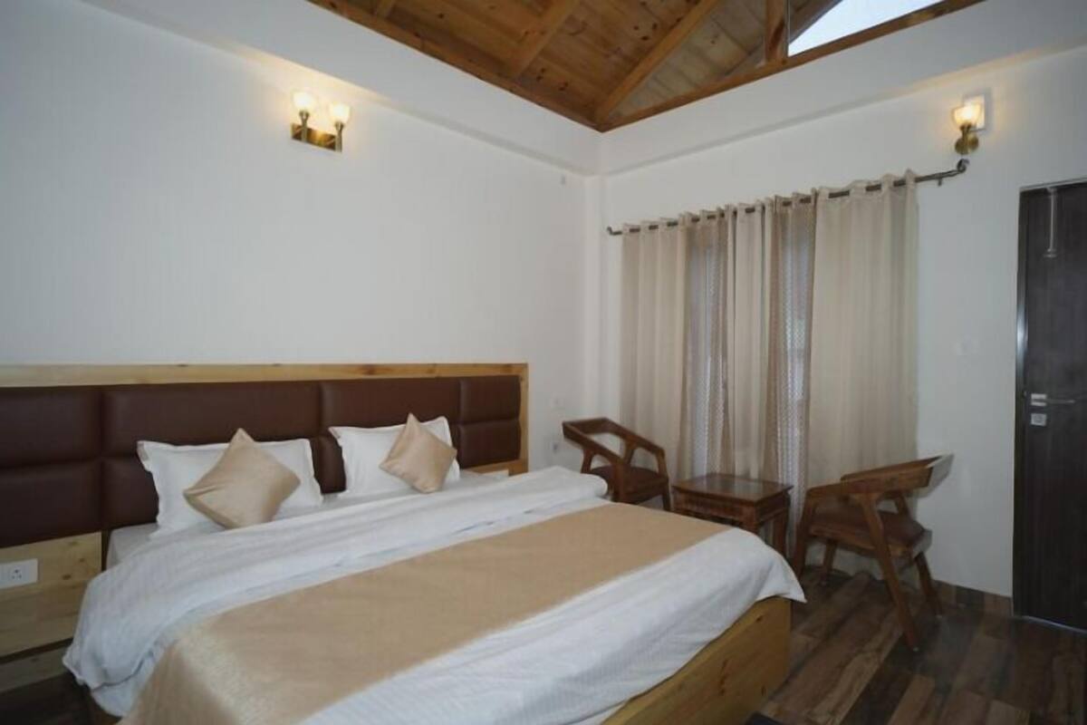 A bedroom with a large bed, wooden headboard, two bedside tables, a desk, and a chair.