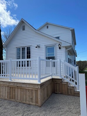 A two-story white house with a wooden deck and a white railing. - The Red Farm Suite at The Red Farm (Howie Centre)
