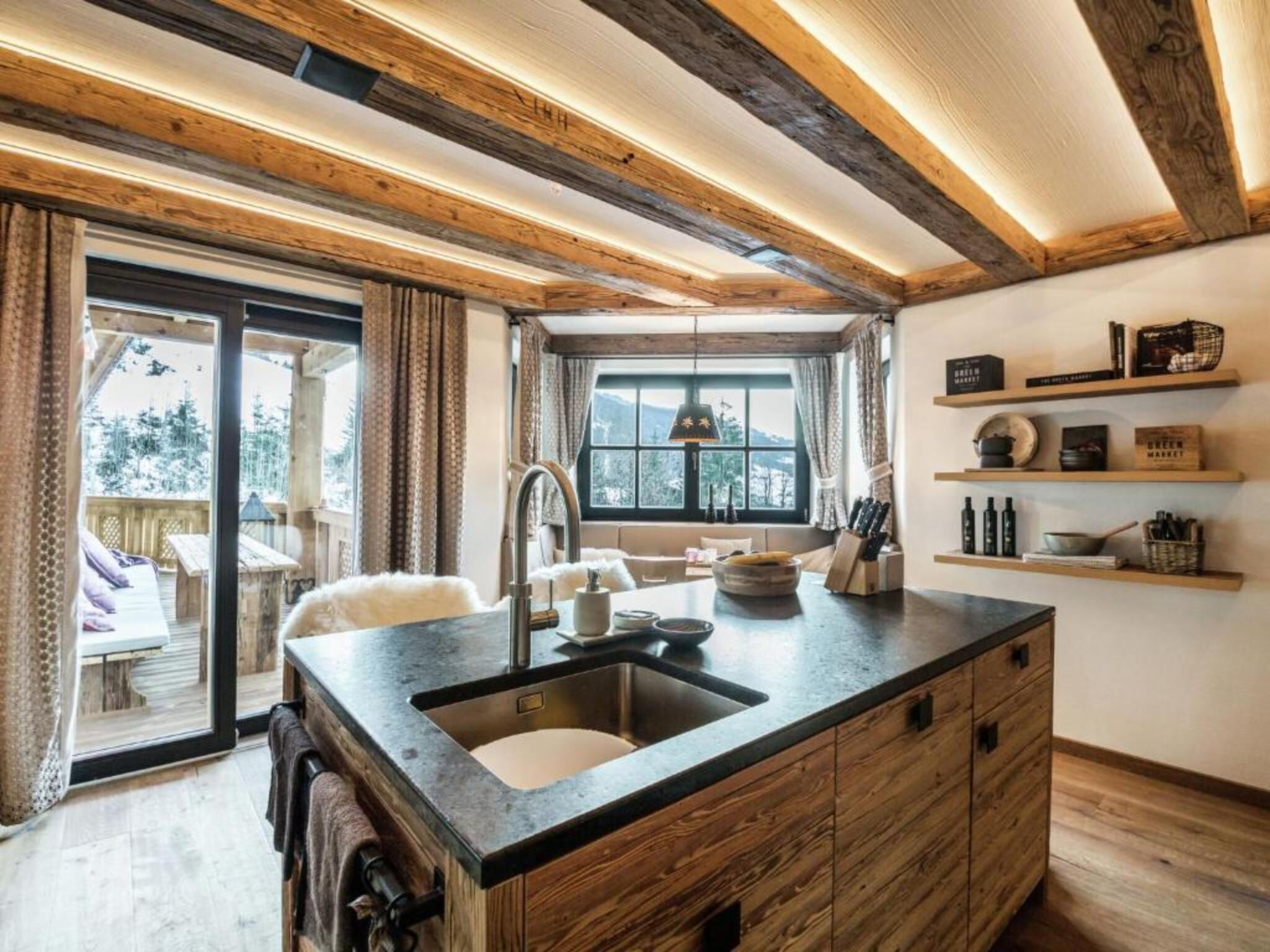 A kitchen with a large island, wooden beams, and a view of the outdoors.