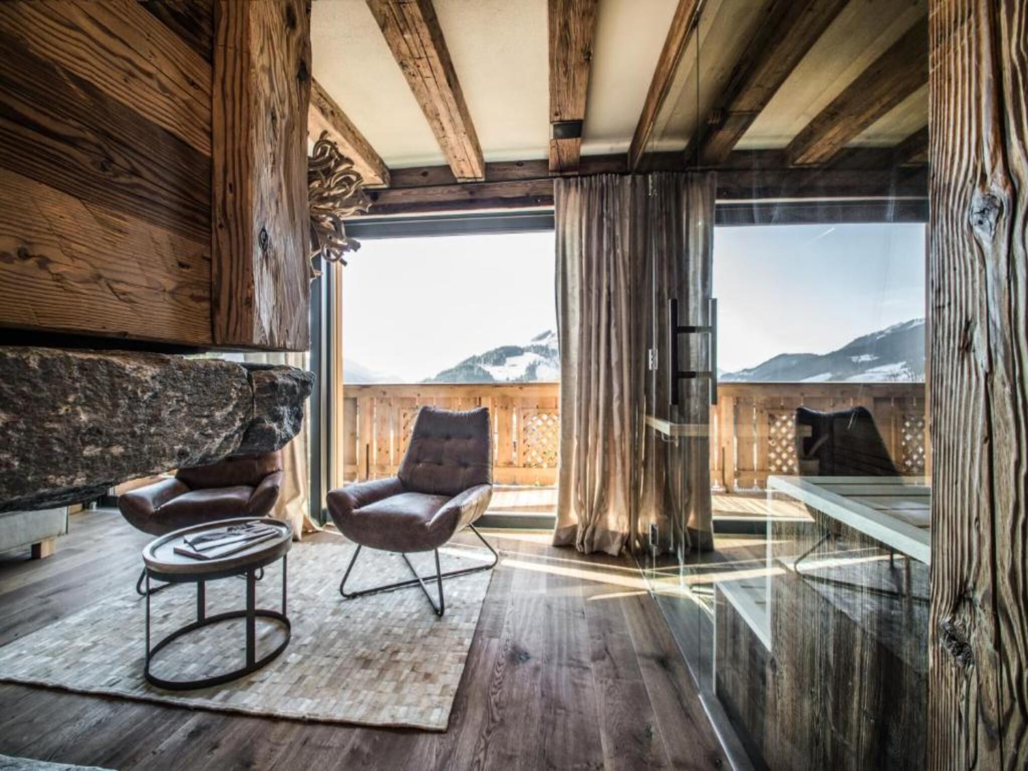 Un intérieur moderne avec des poutres en bois, un mur en pierre et une vue sur les montagnes.