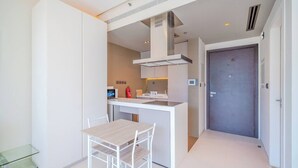 Cozinha compacta com ilha central, armários brancos e micro-ondas.
