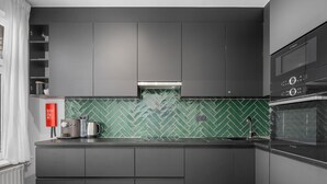 A modern kitchen with dark cabinetry, a herringbone green backsplash, and a Bosch oven. - Renovated apartment for family (Blankenberge)