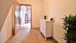 A narrow hallway with a wooden floor, a white radiator, and a small desk with drawers. - Holiday apartment with balcony in Weserbergland (Emmerthal OT Welsede)