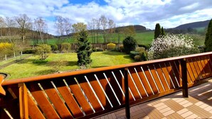 A balcony with a view of a landscaped garden and distant hills. - Holiday apartment with balcony in Weserbergland (Emmerthal OT Welsede)