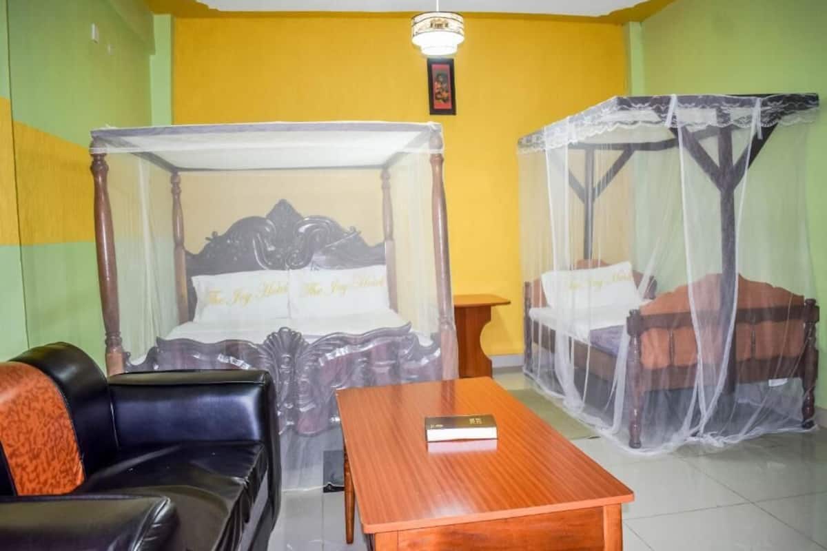 A room with a four-poster bed, a wooden table, and a sofa.