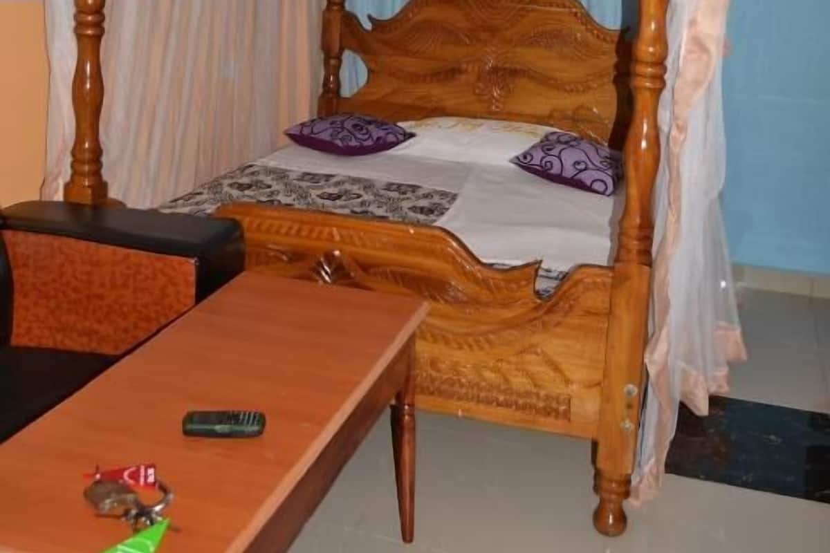 A room with a wooden four-poster bed, a small table, and a hanging light fixture.