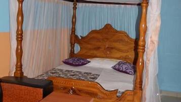 Una habitación con una cama con dosel de madera, una mesita pequeña y una lámpara colgante.