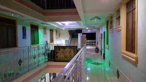 A multi-level corridor with a staircase, railings, and a green-lit area. - The Joy Hotel Voi (Voi)