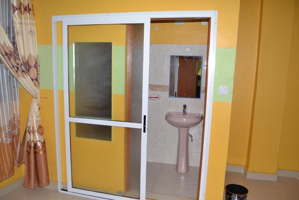 A room with a sliding door leading to a bathroom. The bathroom has a sink and a mirror.
