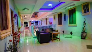 A hotel lobby with a central seating area, a staircase, and a balcony. - The Joy Hotel Voi (Voi)