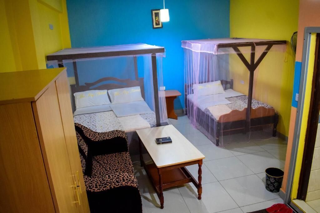 A room with two beds, each with a canopy, a wooden table, and a leopard print sofa.