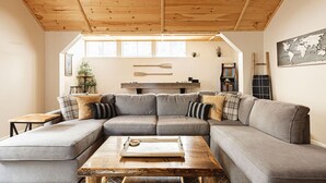 Un salon chaleureux avec un grand canapé d’angle, une table basse en bois et une carte du monde accrochée au mur.