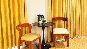 A room with two wooden chairs and a small round table, a water bottle, and a cup on the table. - Foura Suites Makati (Makati)
