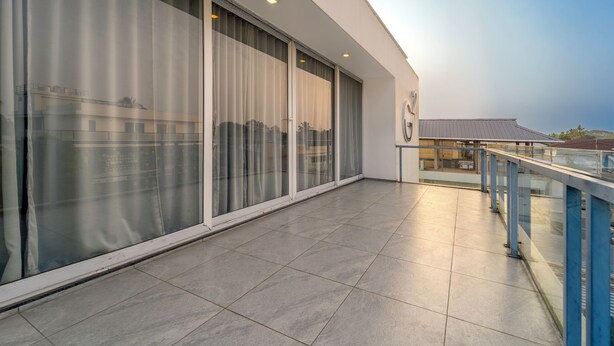 Ein modernes Gebäude mit großen Glasfenstern und einem Balkon mit Metallgeländer.