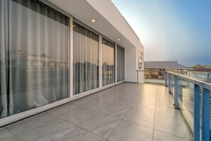 A modern building with large glass windows and a balcony with a metal railing.