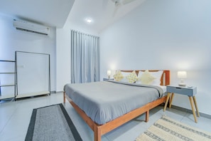 Un dormitorio moderno con cama, mesitas de noche, un escritorio y un armario.
