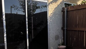 A patio area with a sliding glass door, a wooden fence, and a small brick planter. - Quiet ground floor 2 bedroom- unwind in private. (Garland)