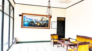 Een kamer met een groot schilderij, een kroonluchter en klassiek meubilair.