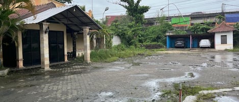 Un edificio con vestíbulo cubierto y un patio empedrado con charcos.