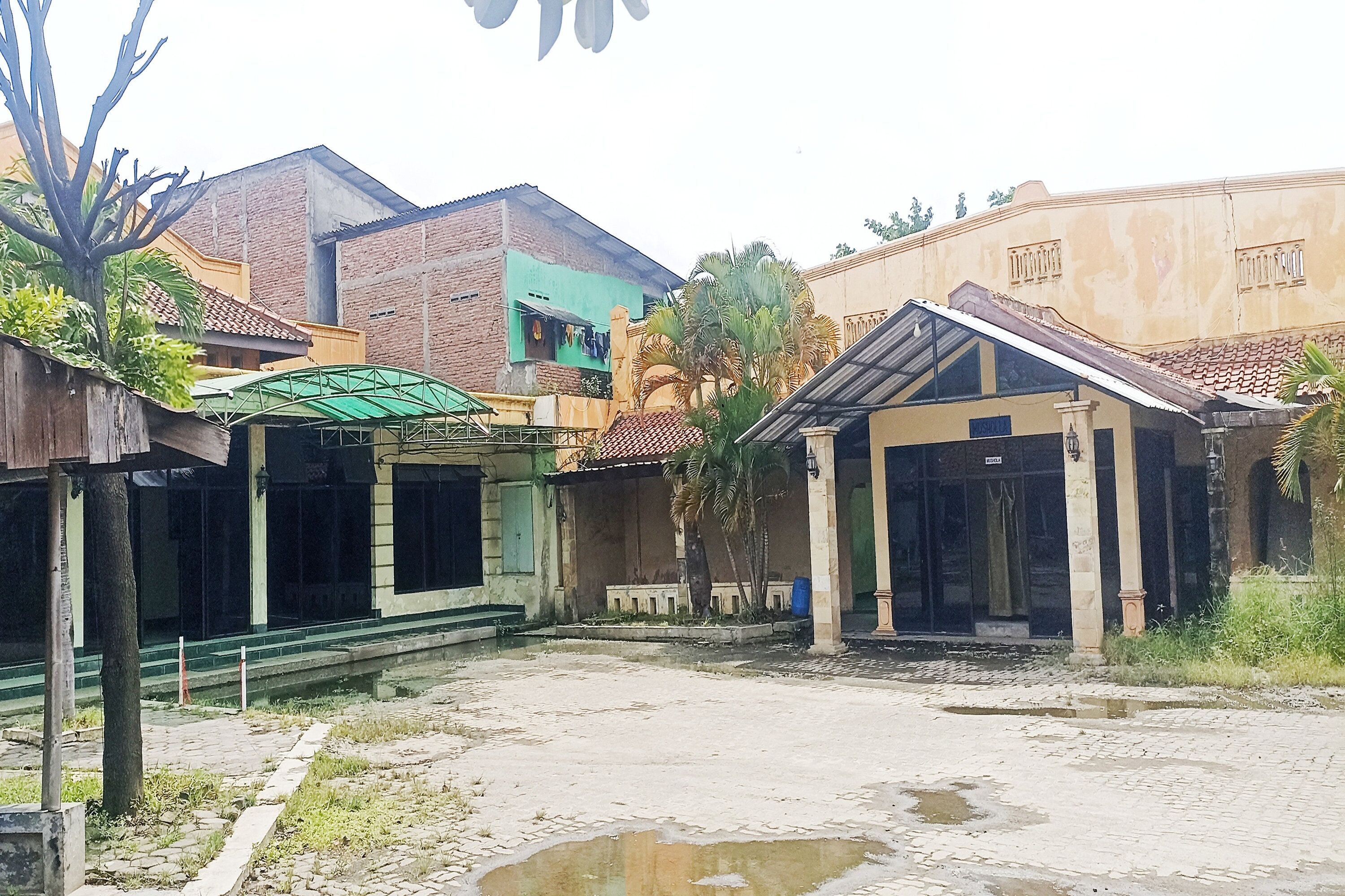 A courtyard with a paved area, a small covered structure, and a building with a green awning.