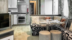 Une cuisine moderne dotée d’un four encastré, d’un coin repas avec une table ronde et d’un téléviseur posé sur un meuble.