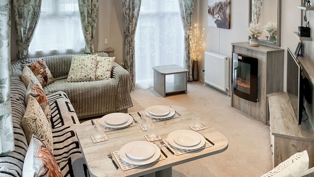 Un salon chaleureux avec un canapé, une table à manger dressée pour quatre personnes, une cheminée et un radiateur.
