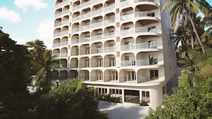 Un hôtel à plusieurs étages, doté d’une façade incurvée, de nombreux balcons et d’un espace piscine au rez-de-chaussée.
