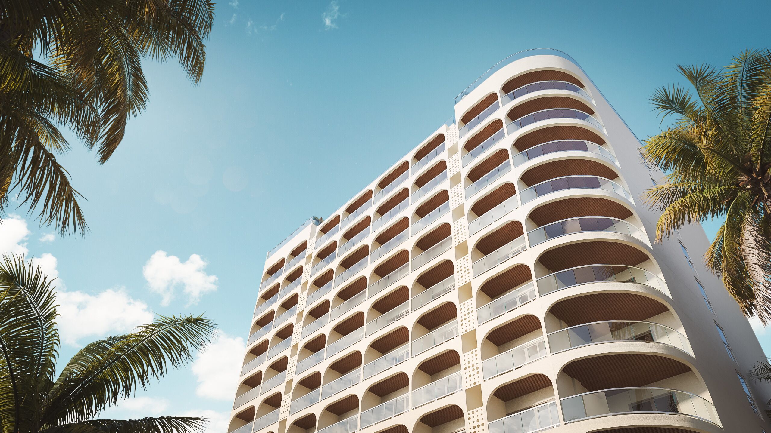 Un hotel de varios pisos con una fachada curva, numerosos balcones y palmeras en primer plano.