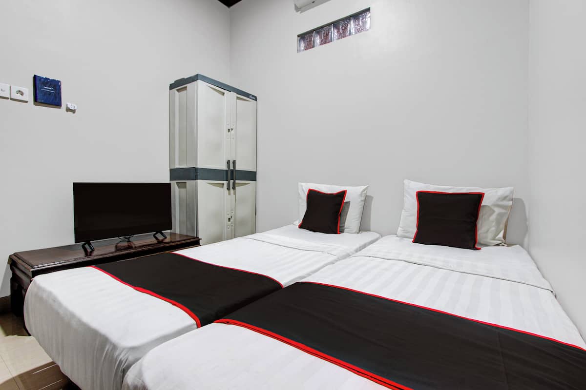 Habitación de hotel con dos camas, televisión, armario y ventana pequeña.