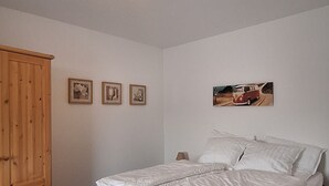 A bedroom with a bed, a wooden wardrobe, and three framed pictures on the wall. - A cozy vacation apartment in a charming former hotel. (Sankt Andreasberg)