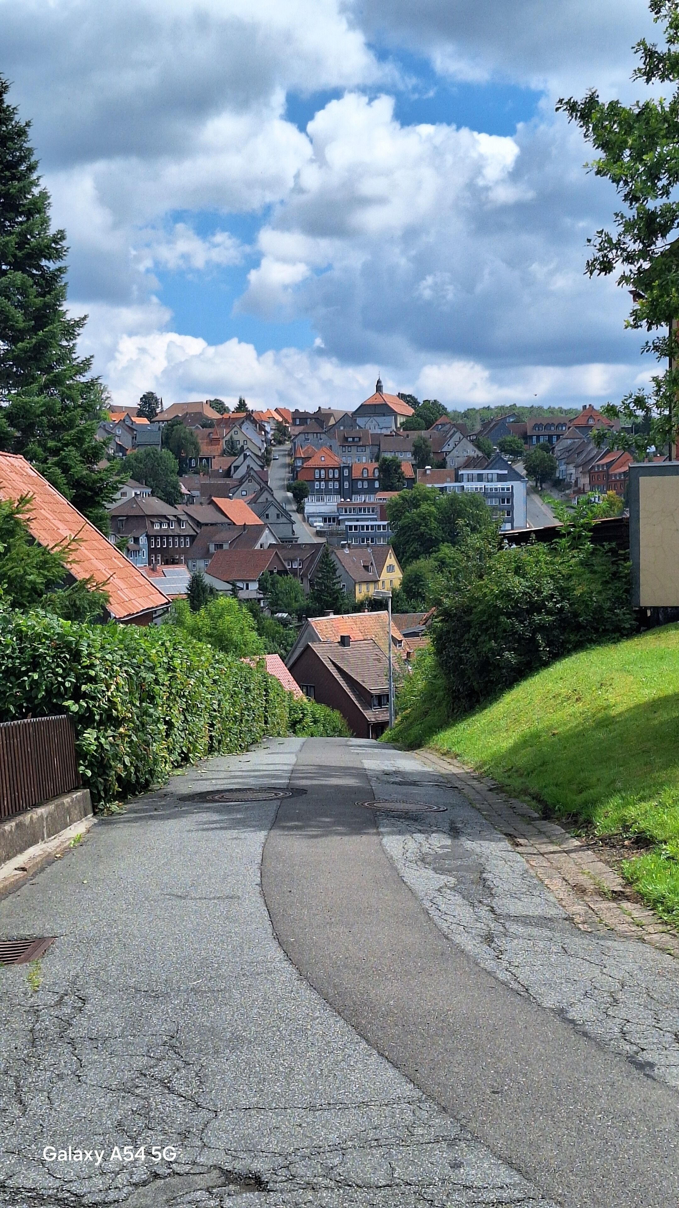 Een woonstraat met huizen, een bochtige weg en een gazon.