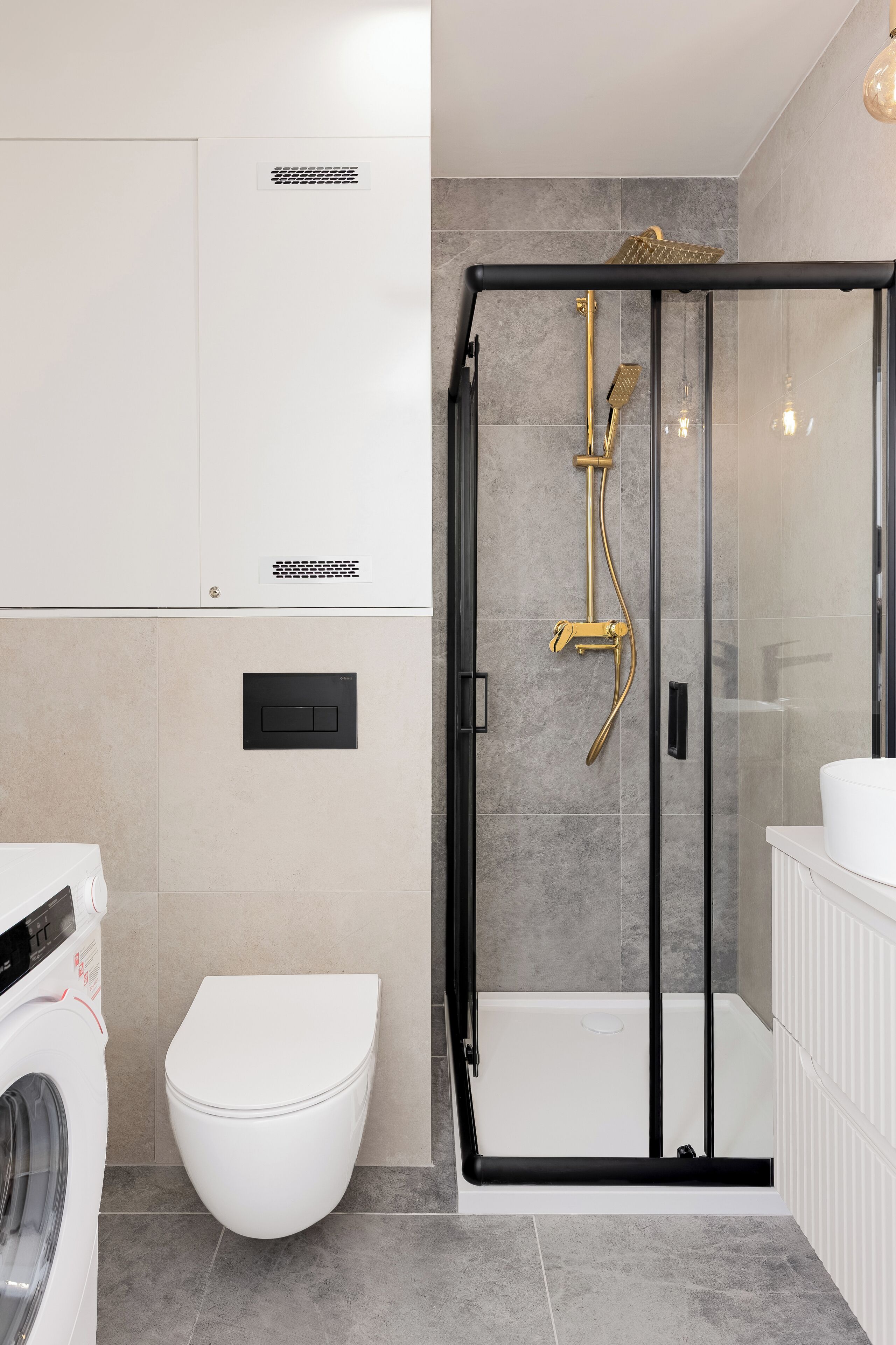 A modern bathroom with a glass-enclosed shower, a white toilet, and a washing machine.