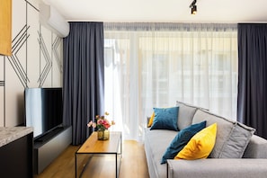 Un salon moderne avec un canapé, une table basse et un téléviseur.