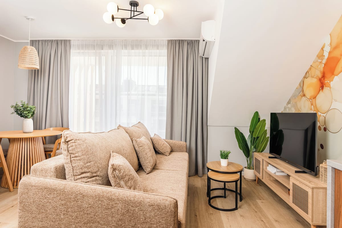 Ein modernes Wohnzimmer mit Sofa, Fernseher und Essbereich.